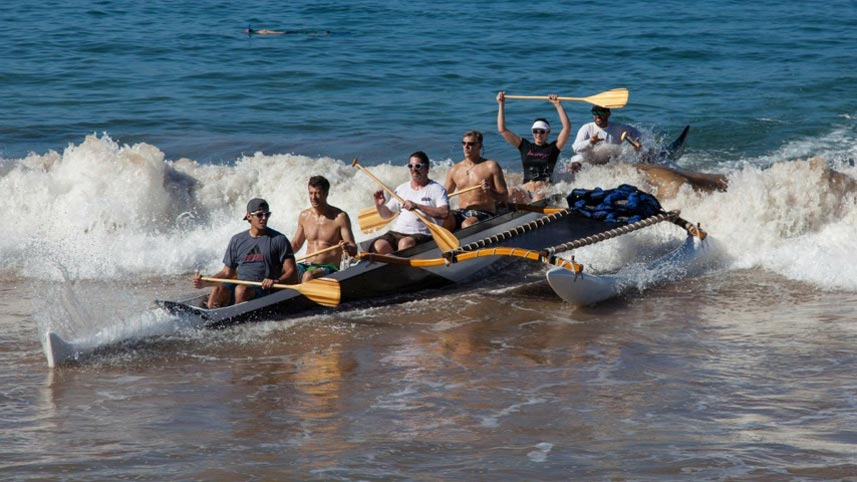 Six digital foundry software engineers and consultants ride a wave back to shore in an outrigger canoe in Hawaii