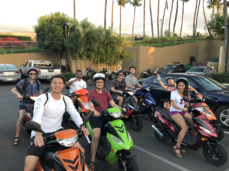 A group of 8digital foundry software engineers and consultants sit on scooters in a parking lot in hawaii.