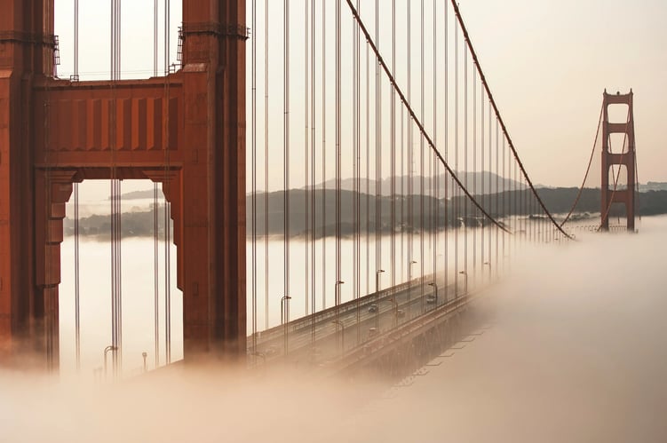The golden gate bridge in morning light with low golden fog partly covering the deck. The golden gate bridge in morning light with low golden fog partly covering the deck.