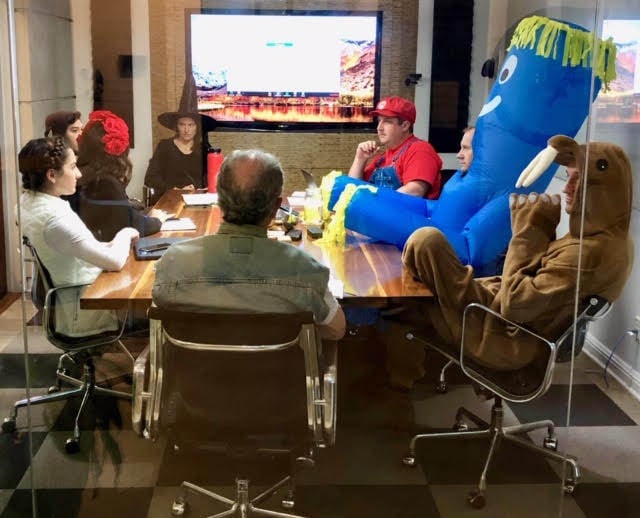 Eight team members focused in a conference despite some silly Halloween costumes