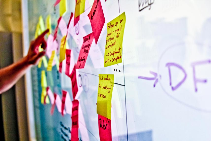 Multicolored sticky notes on a glass conference-room wall.